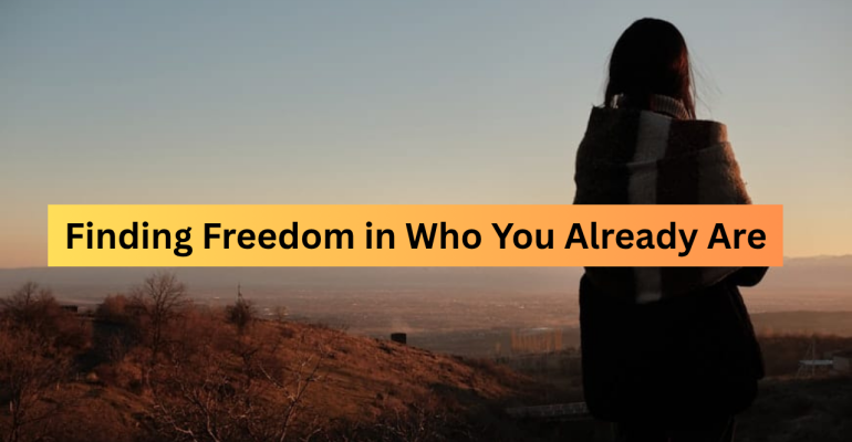 A woman wrapped in a blanket stands on a hill at sunset, gazing at distant mountains — symbolizing freedom, reflection, and self-acceptance.