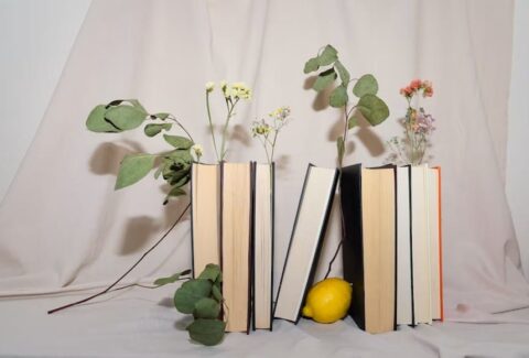 A stack of books beside fresh flowers, representing Women's History Month, literature, and reflective reading.