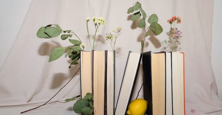 A stack of books beside fresh flowers, representing Women's History Month, literature, and reflective reading.