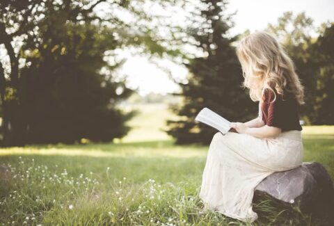 A person reading a book in natural morning light, symbolizing reflection, hope, and the positive influence of thoughtful reading.