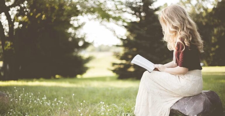 A person reading a book in natural morning light, symbolizing reflection, hope, and the positive influence of thoughtful reading.