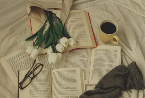 An open book surrounded by fresh flowers in natural light, symbolizing reflection, storytelling, and the enduring impact of women's voices in literature.