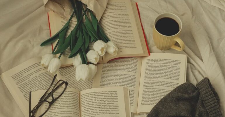 An open book surrounded by fresh flowers in natural light, symbolizing reflection, storytelling, and the enduring impact of women's voices in literature.