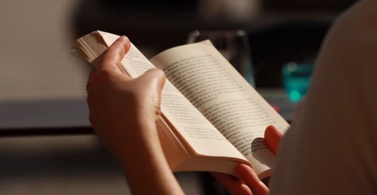 Woman reading a book beside a window, reflecting the themes of self-discovery, personal reflection, and new possibilities